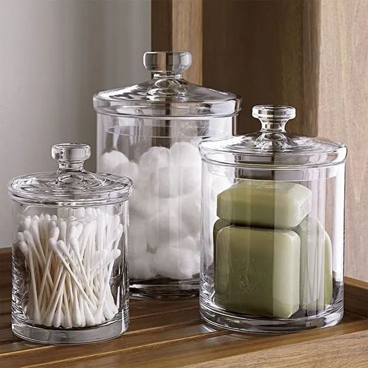 Glass apothecary jars holding cotton and soap for bathroom storage